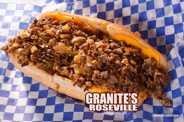 Loaded Philly cheesesteak with melted cheese on blue checkered paper